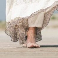 Low angle close up female feet walking forward at the beach